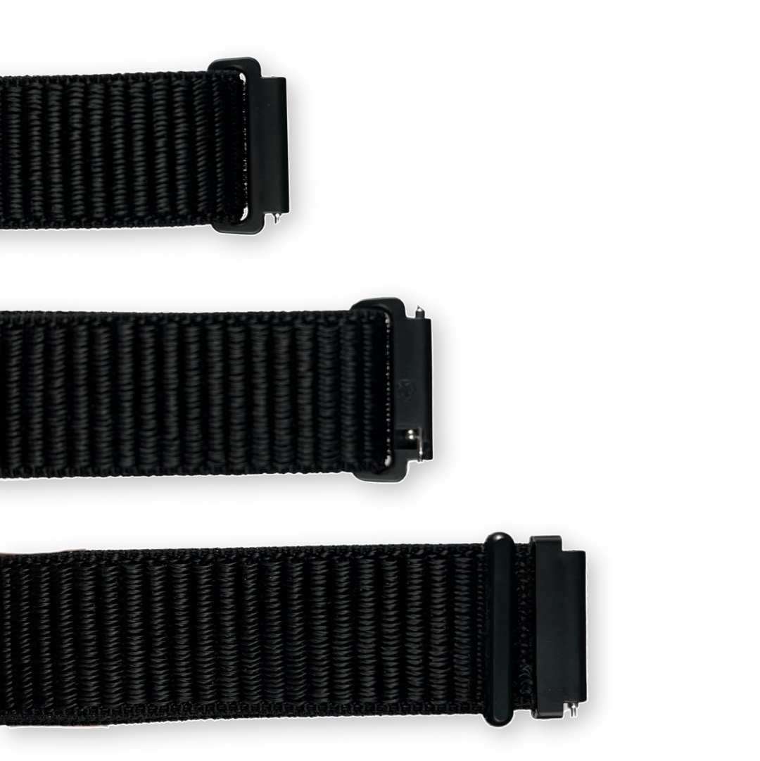 Tři části černého textilního řemínku s plastovými černými úchyty a kovovými čepy pro upevnění k hodinkám.